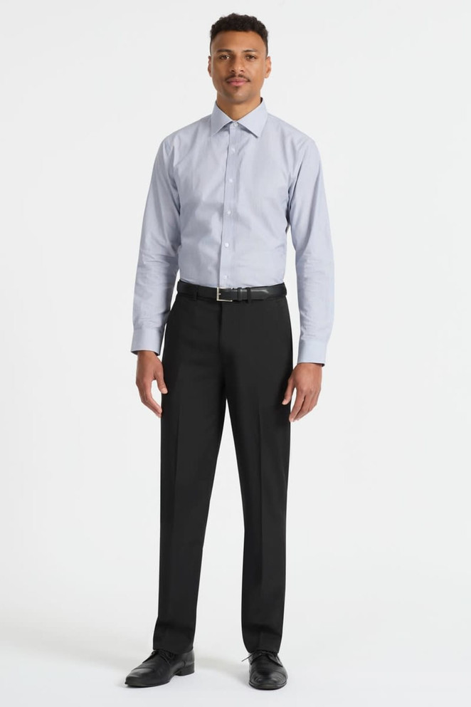 A man wears a light blue long sleeve button-up shirt paired with black trousers and shoes. The shirt features a logo.