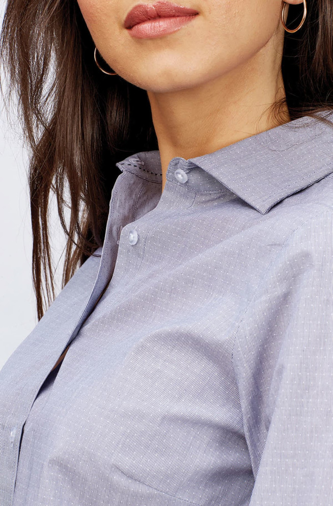 A close-up of a women's button-up shirt in light blue with subtle patterns, featuring a collar and button details.