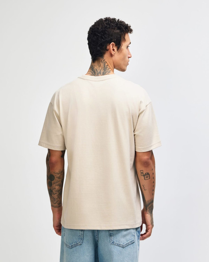 A light beige, unisex heavyweight t-shirt featuring a plain back design. It has a logo on the garment.