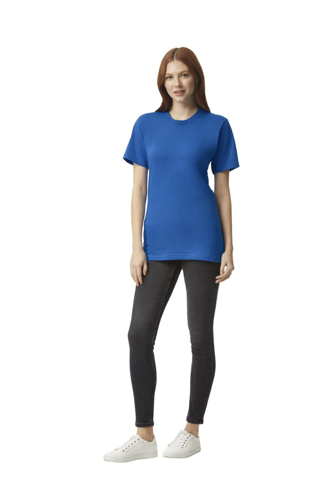 A woman stands wearing a blue unisex fine jersey short sleeve t-shirt and black leggings, with white shoes.