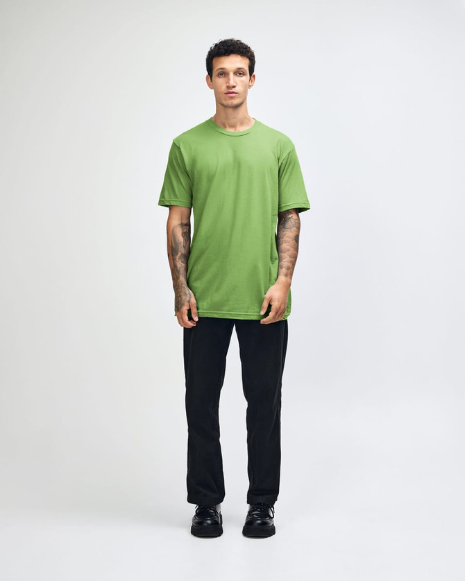 A unisex fine jersey short sleeve T-shirt in vibrant green, worn by a model in casual denim. It features a logo.