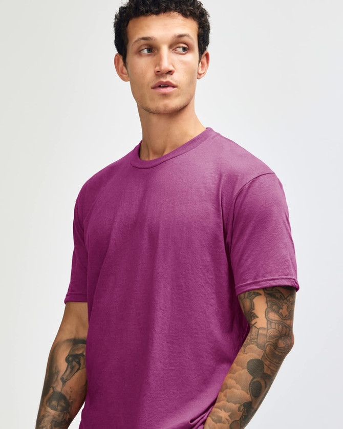 A unisex short sleeve t-shirt in a vibrant magenta colour, worn by a model with a neutral expression.
