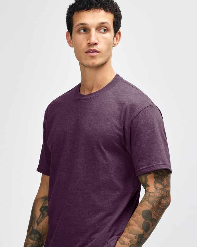 A unisex short sleeve t-shirt in a deep purple colour, displayed by a model. Features a plain design with a logo.