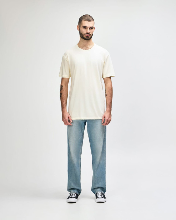 A white Gildan Softstyle adult T-shirt displayed on a model, paired with light blue jeans. The model stands against a neutral background.