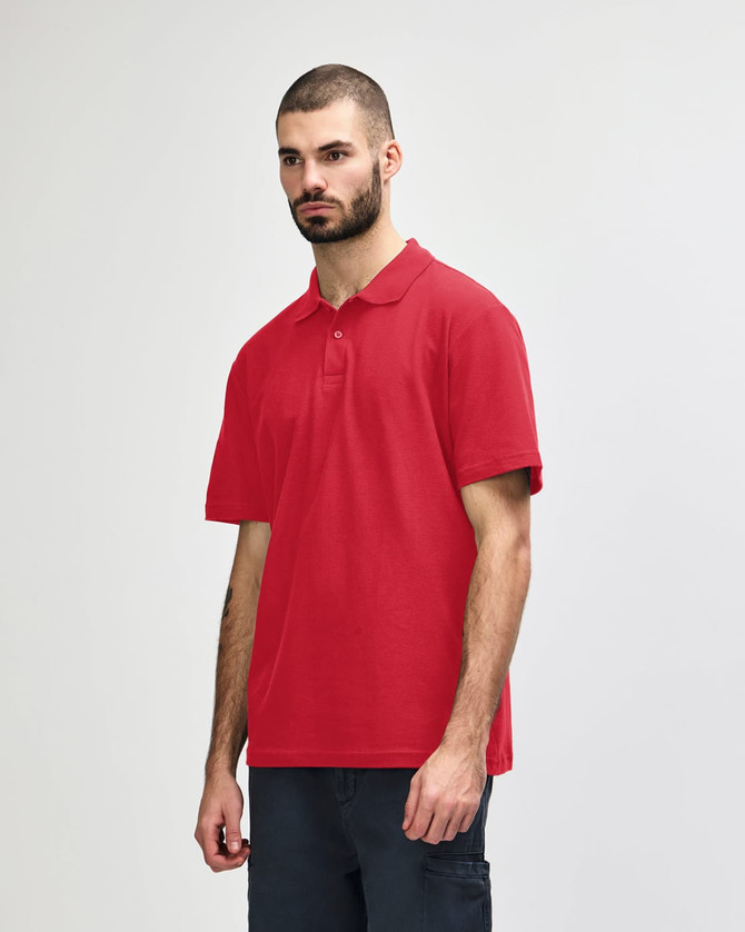 A red Gildan Softstyle adult double pique polo, featuring a collar and short sleeves. The model stands against a neutral background.