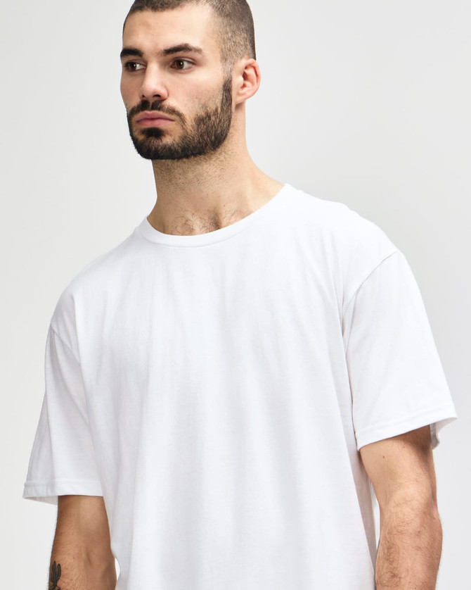 A model wearing a plain white Gildan Softstyle adult midweight T-shirt, featuring a simple design and a logo.