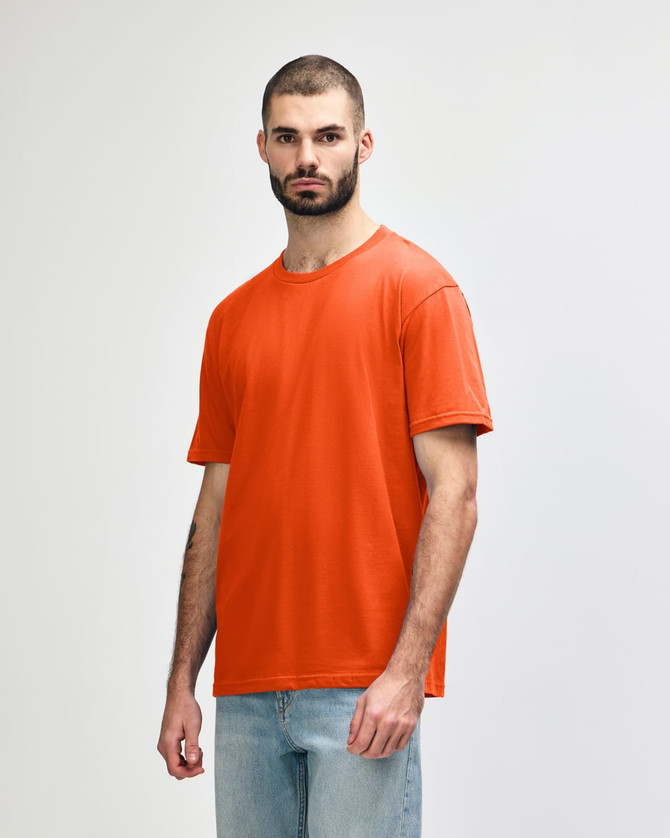 An orange Gildan Softstyle adult midweight T-shirt displayed on a model standing in a neutral stance.
