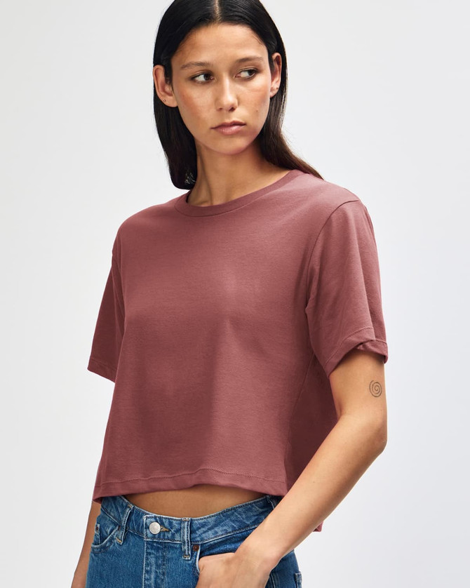 A model wearing a boxy, short-sleeved fine jersey T-shirt in a muted rose colour, paired with light denim shorts.