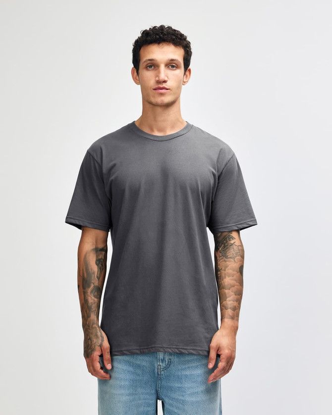 A grey unisex short sleeve T-shirt displayed on a model with tattoos, featuring a simple design and relaxed fit.
