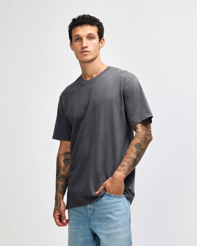 A grey sueded unisex short sleeve T-shirt displayed on a model with tattoos, featuring a brand logo.