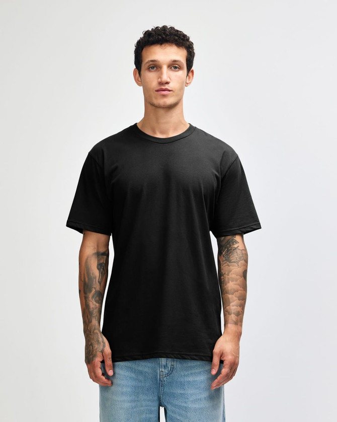 A black unisex short sleeve t-shirt on a model with tattoos, featuring a simple design and relaxed fit.