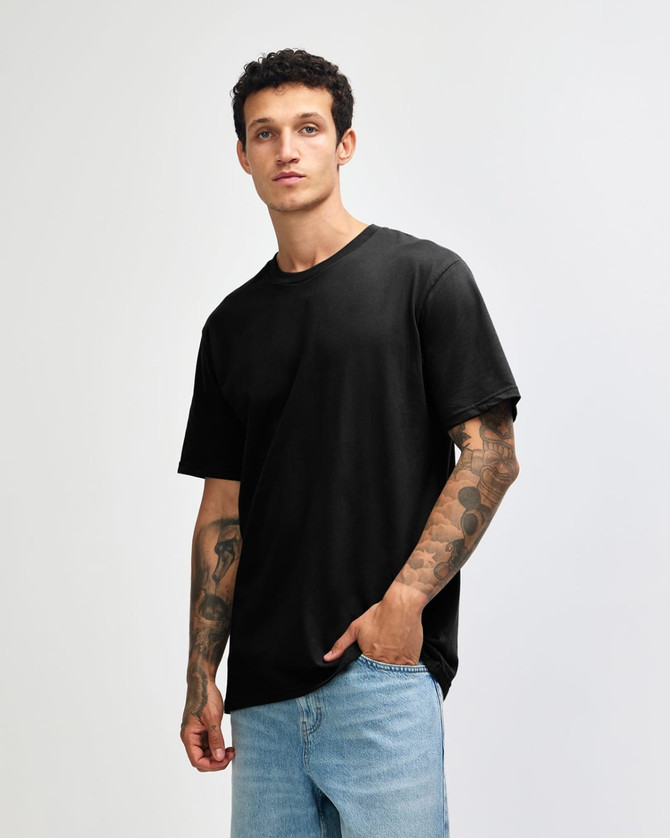 A black sueded unisex short sleeve T-shirt displayed on a model with tattoos, paired with light blue jeans.