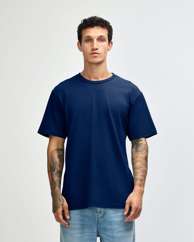 A navy unisex short sleeve T-shirt displayed on a model with tattoos, featuring a simple design and no visible branding.