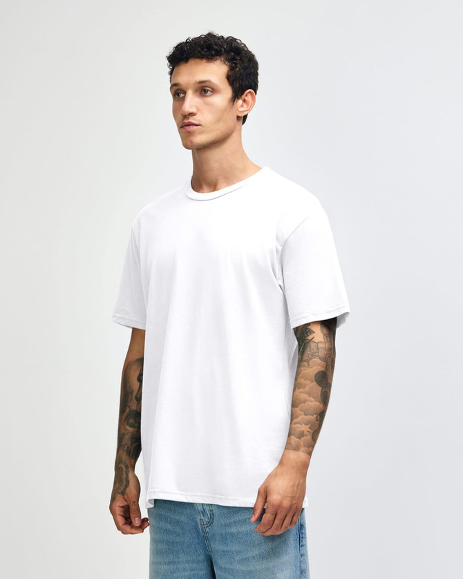 A white unisex short sleeve T-shirt displayed on a model with tattoos, featuring a simple design and relaxed fit.