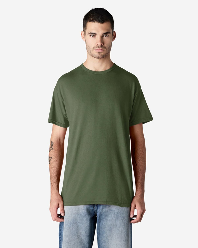 A man wearing a green Gildan Light Cotton T-Shirt, standing against a plain background, with blue jeans.