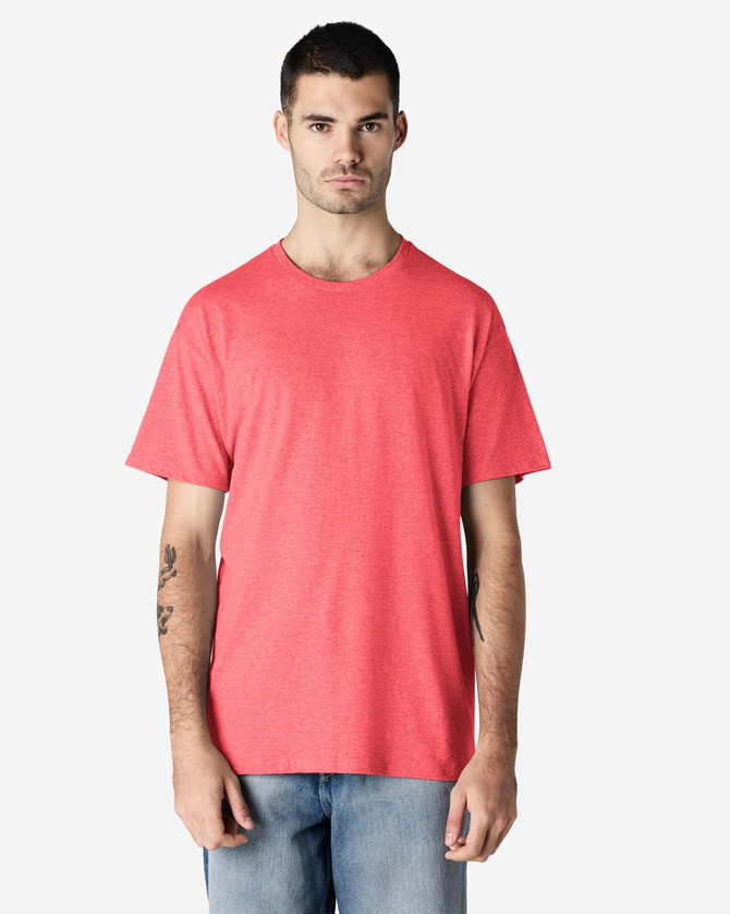 A man in a bright pink Gildan Light Cotton T-Shirt stands against a plain background. The shirt has a logo.