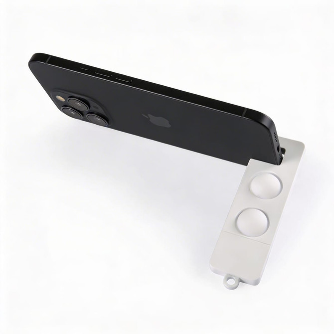 A white phone stand supports a black smartphone, featuring two circular grips for stability.