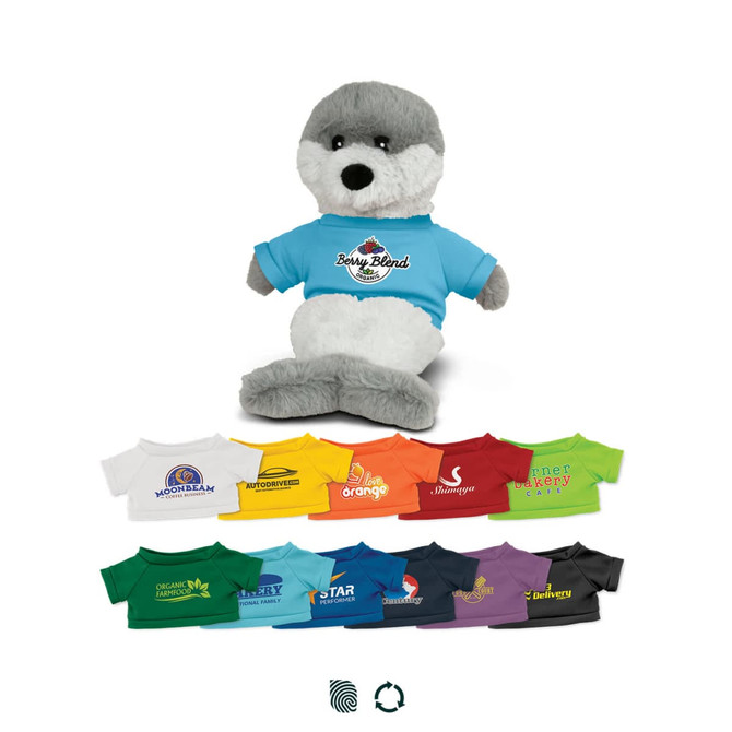 A grey and white seal plush toy wearing a blue shirt, surrounded by various smaller shirts in different colours.