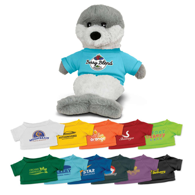 A grey and white seal plush toy wearing a blue shirt features various colourful t-shirts below it with branding.