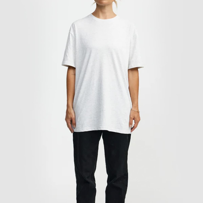 A white essential T-shirt, with short sleeves, displayed on a model, paired with black trousers. The shirt has a branding logo.