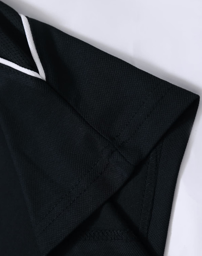 A black polo shirt featuring a collar and cuff detail, with a subtle logo on the sleeve.
