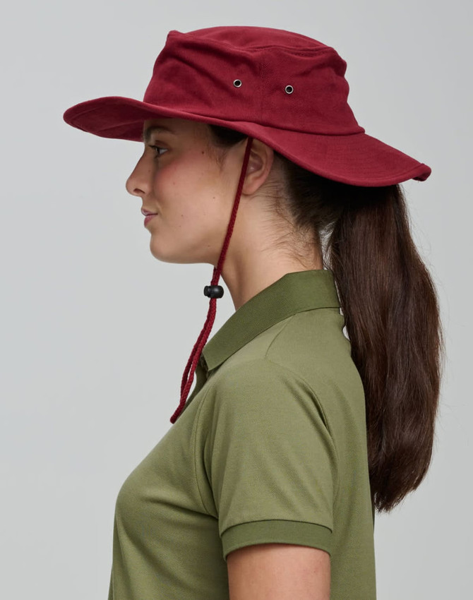 A burgundy surf hat with a wide brim and adjustable chin strap, worn by a person in profile.