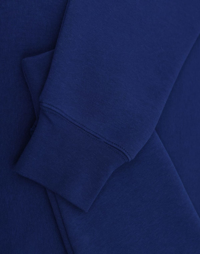 A blue crewfleece jumper featuring a close-up of the sleeve and cuff details. It has a small logo.