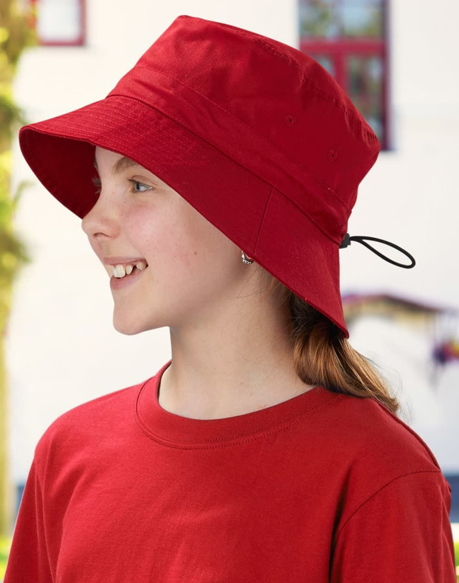 A red bucket hat with a toggle feature, worn by a child, alongside a matching red shirt. The hat has a logo.