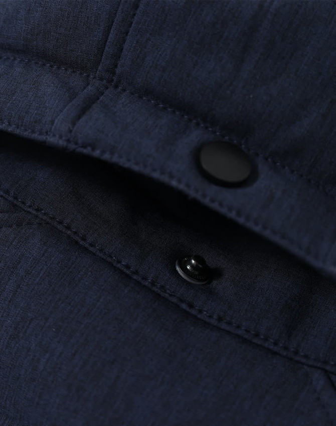 A close-up of a navy blue softshell hoodie featuring snaps and stitching details. The fabric appears sturdy and textured.