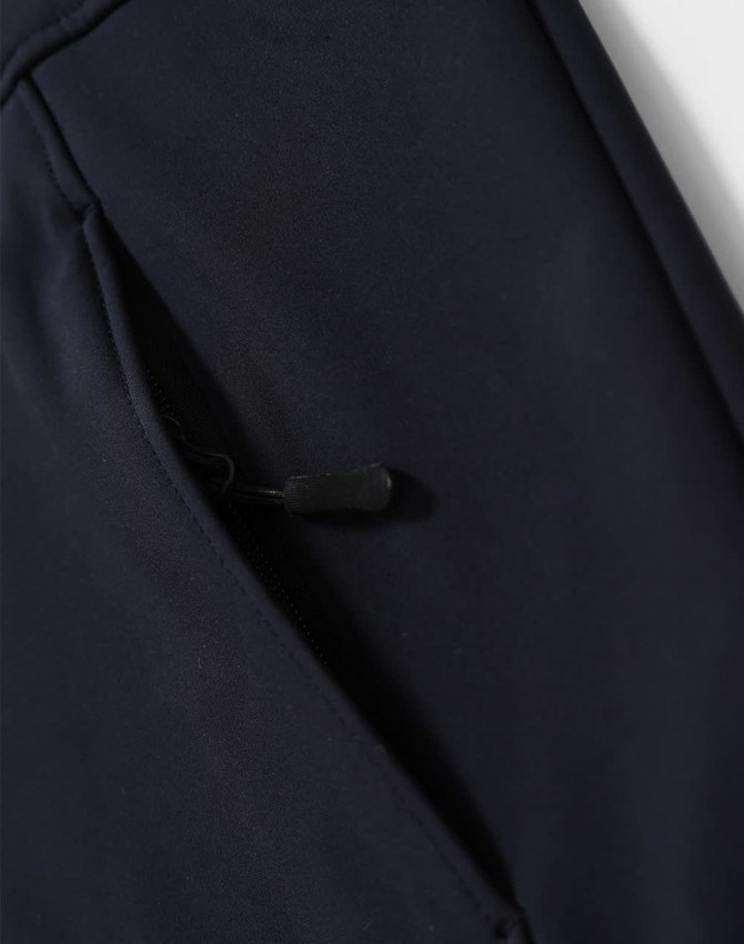 A navy softshell full zip hoodie featuring a zippered pocket on the side and a logo.