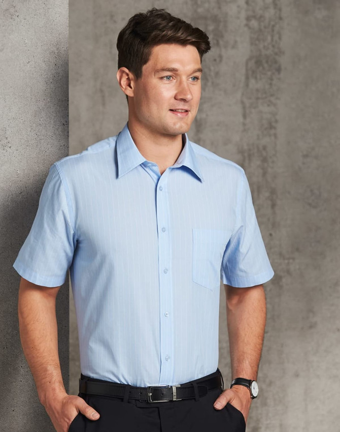 A short sleeve button-up shirt in light blue with subtle pin stripes and a chest pocket, worn by a man.