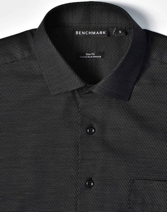 A black pin dot stretch short-sleeve button-up shirt featuring a collar, buttons, and a pocket. It includes branding on the collar.