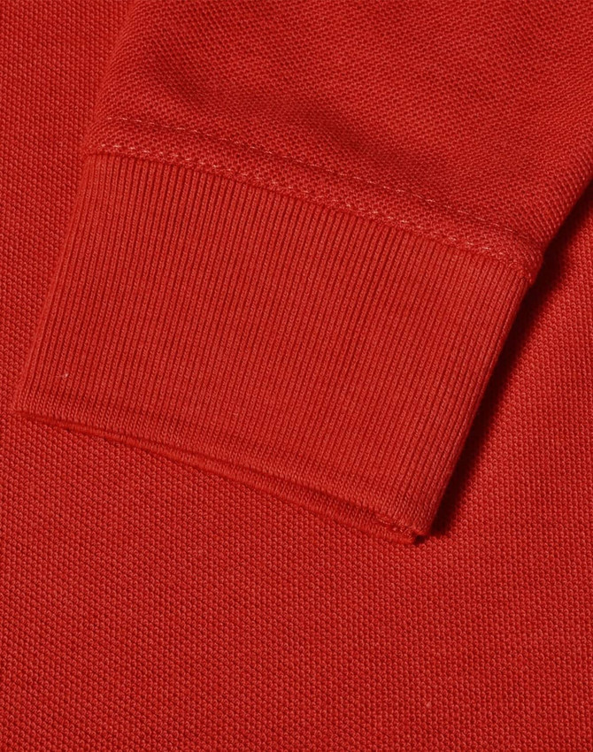 A close-up of a red long sleeve polo shirt, featuring a ribbed cuff and textured fabric.