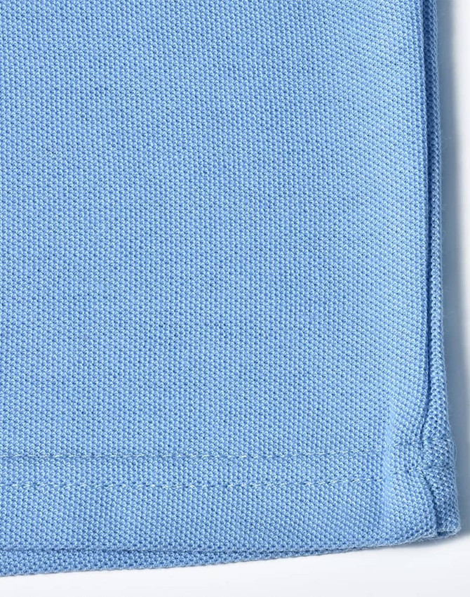 A blue traditional poly/cotton pique knit long sleeve polo shirt with a hem detail and a logo.