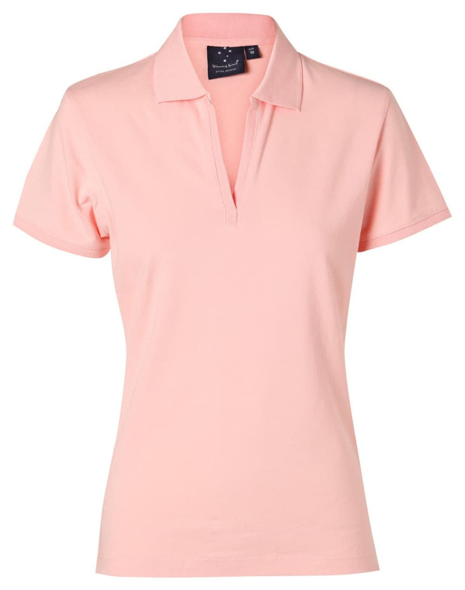 A ladies' polo shirt in a soft pink colour, featuring a collar and a branded tag.