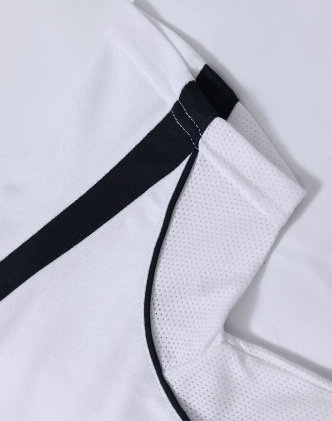 A white polo shirt with black trim and a textured fabric. It has a logo featured on it.