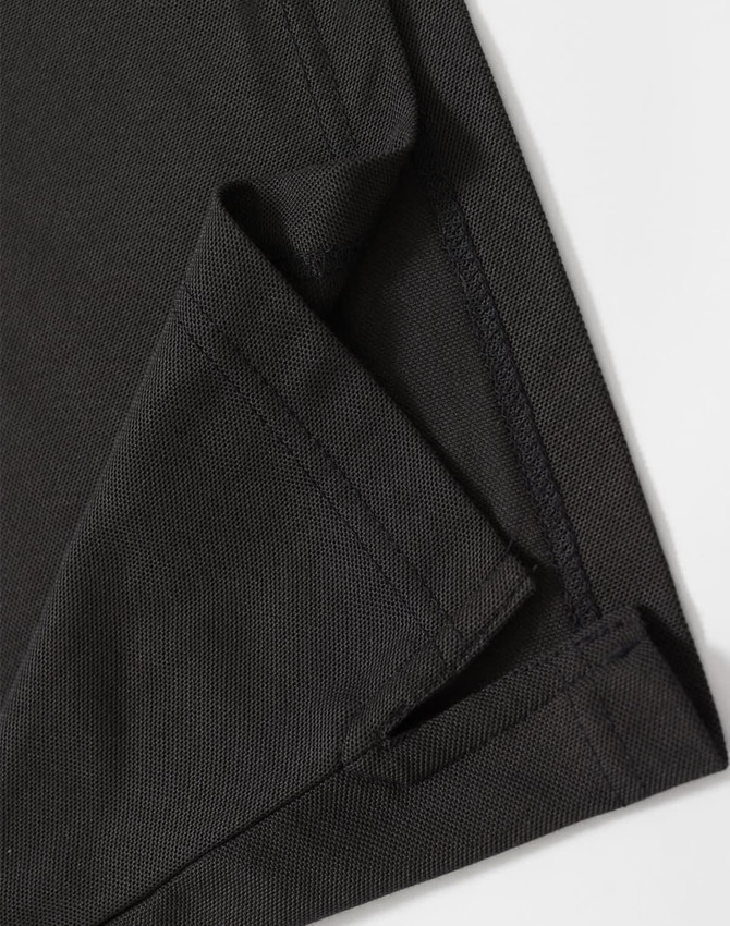 A close-up of a black polo shirt featuring a neatly stitched hem and collar. The fabric texture is visible.