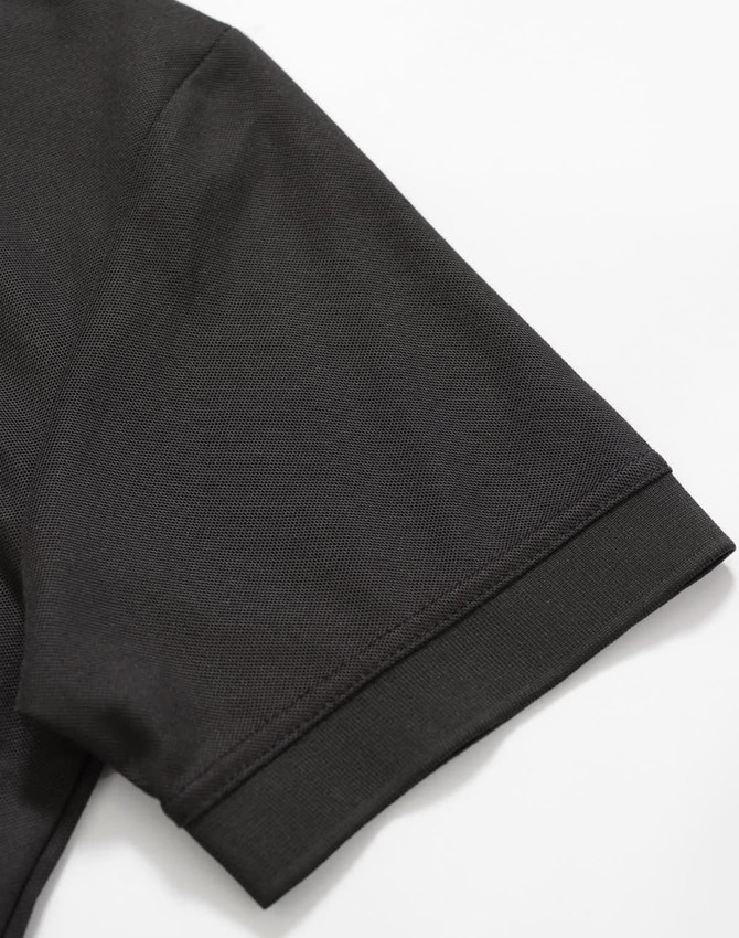 A black polo shirt featuring a smooth fabric texture and neatly finished sleeve hem. It also has a logo.