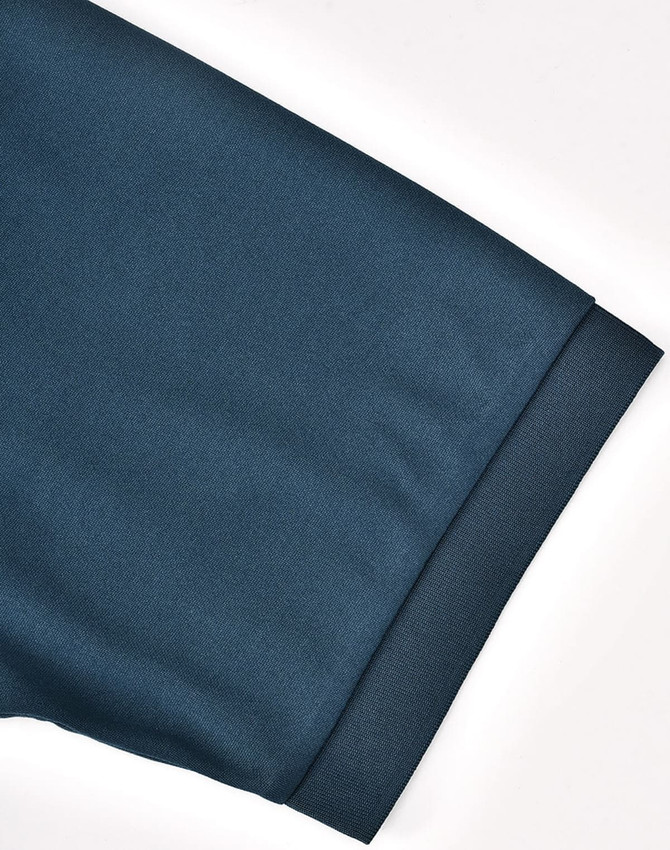 A close-up of a dark teal polo shirt sleeve, featuring a smooth texture and a hemmed cuff.
