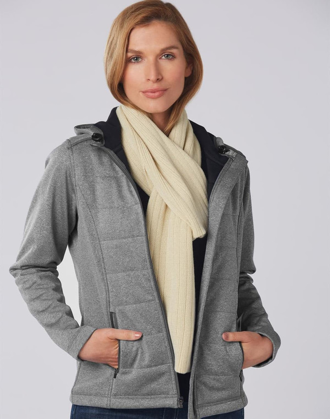 A model wearing a cream cable knit scarf layered over a grey jacket. The scarf features a textured cable row design.