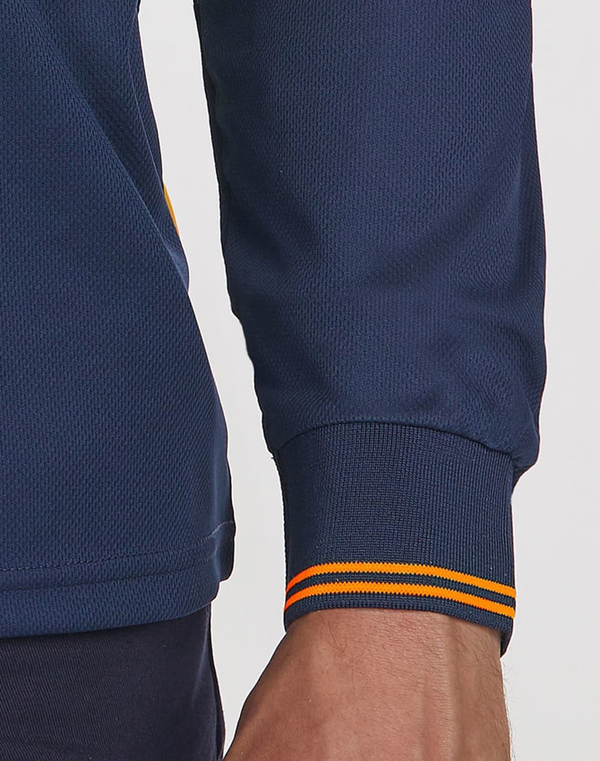 A close-up of a navy blue long-sleeved polo shirt with segmented orange-striped cuffs, featuring a logo.