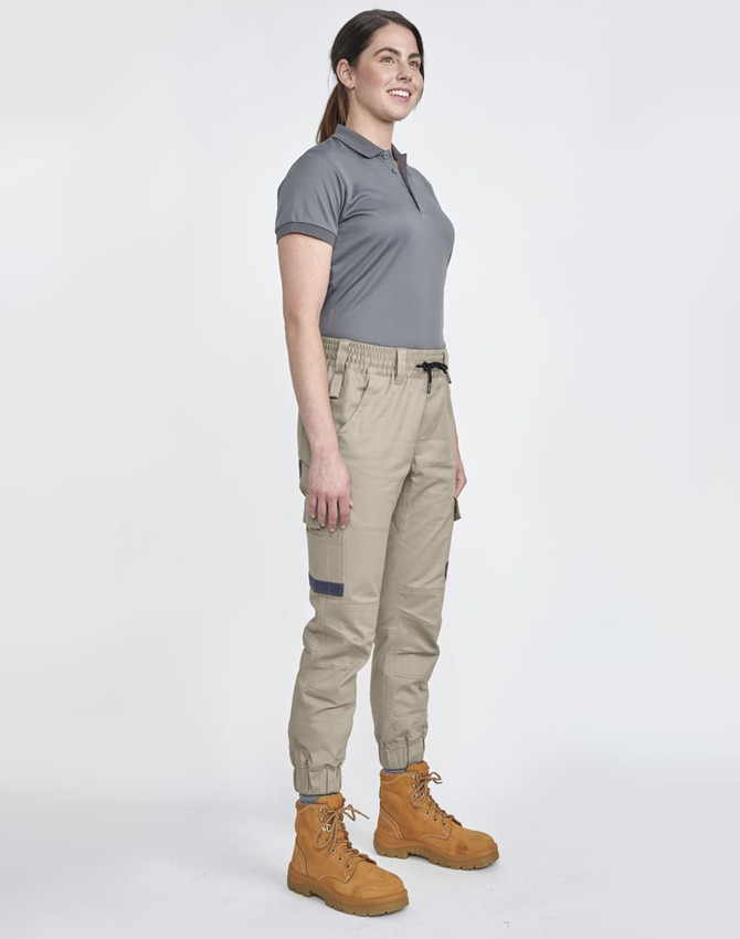 Unisex cotton stretch drill cuffed work pants in khaki, paired with a grey polo and tan work boots. Features pockets and an elastic waistband.