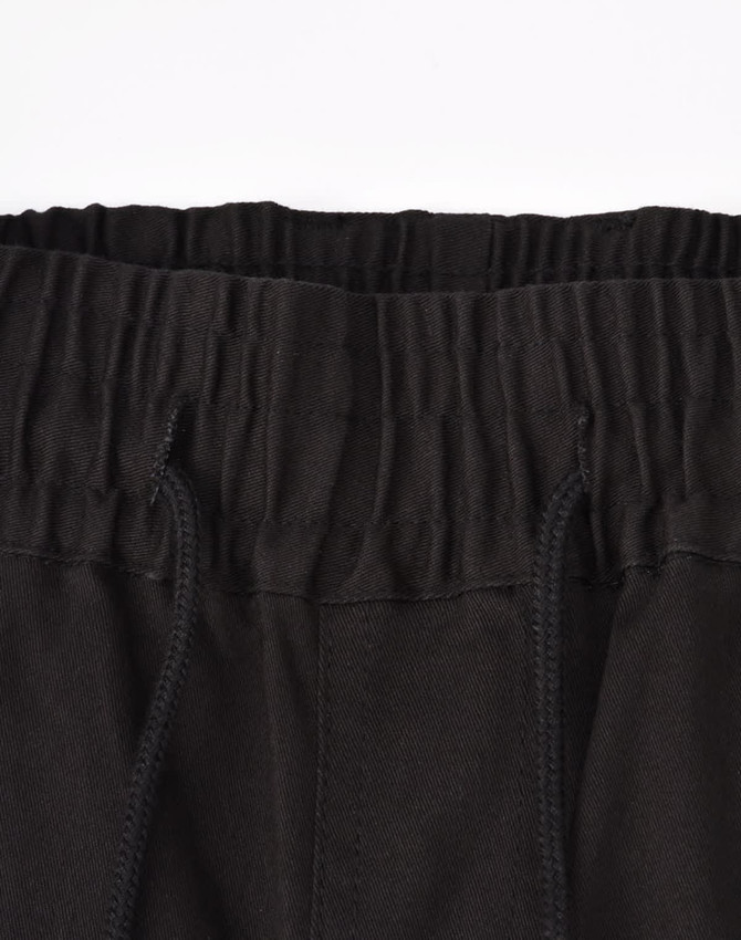 A close-up of unisex cotton stretch drill cuffed work pants in black, featuring an elastic waistband and drawstring.