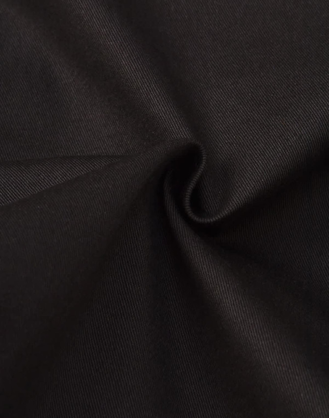 A close-up of black cotton fabric, showcasing a smooth texture and slight stretch. The material appears to be durable.