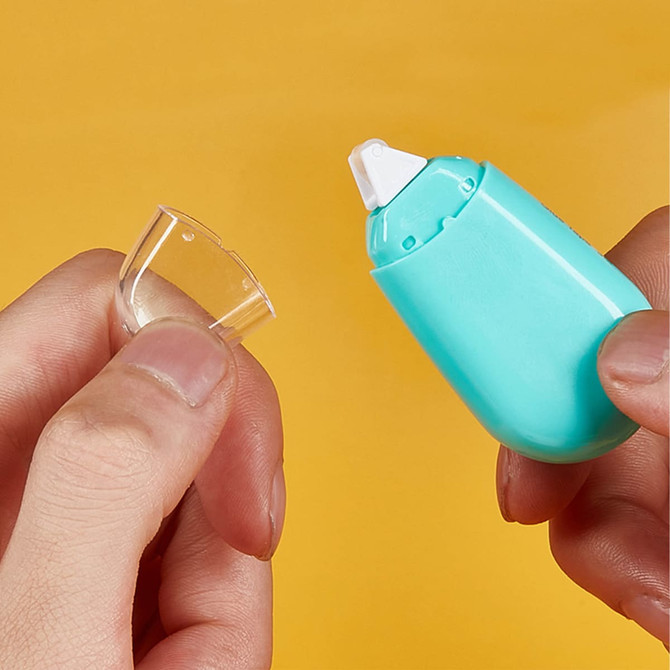 A turquoise glue tape dispenser with a white tip, held alongside a clear protective cap.