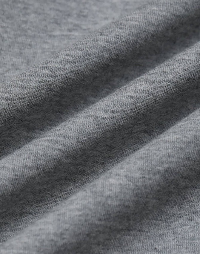 A close-up of grey fabric featuring a soft, textured surface, showcasing the CVC material of the crew neck sweater.