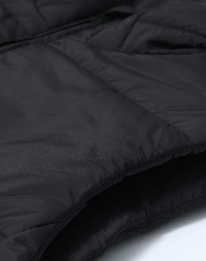 A close-up of a black insulated puffer vest featuring a 3D cut and a textured fabric. The image includes branding.