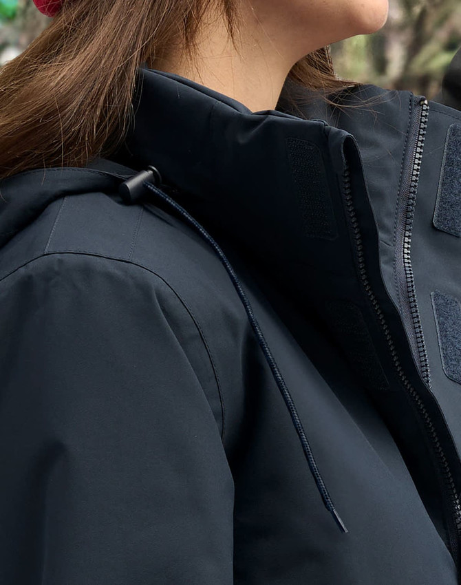 A unisex quilted waterproof jacket in navy blue, featuring a zip and adjustable hood, with a branding logo visible.