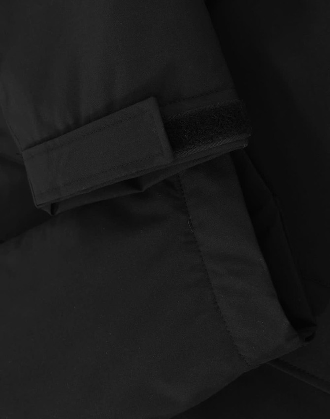 A close-up of a black unisex quilted waterproof jacket featuring a Velcro cuff and smooth fabric texture.