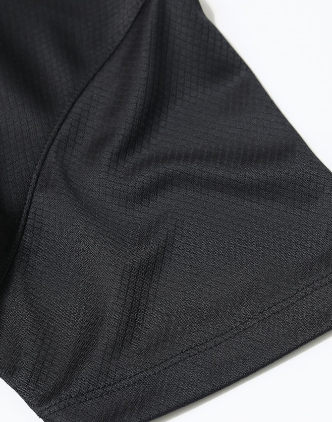 A close-up of a black jacquard knit fabric, highlighting the texture and stitching details of a polo shirt.